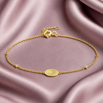 Gouden armband met vingerafdruk op rond bedeltje
